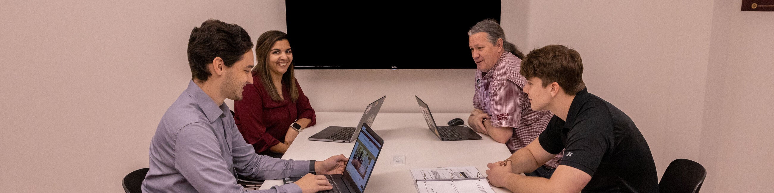 One female employee and three male employees meeting. 
