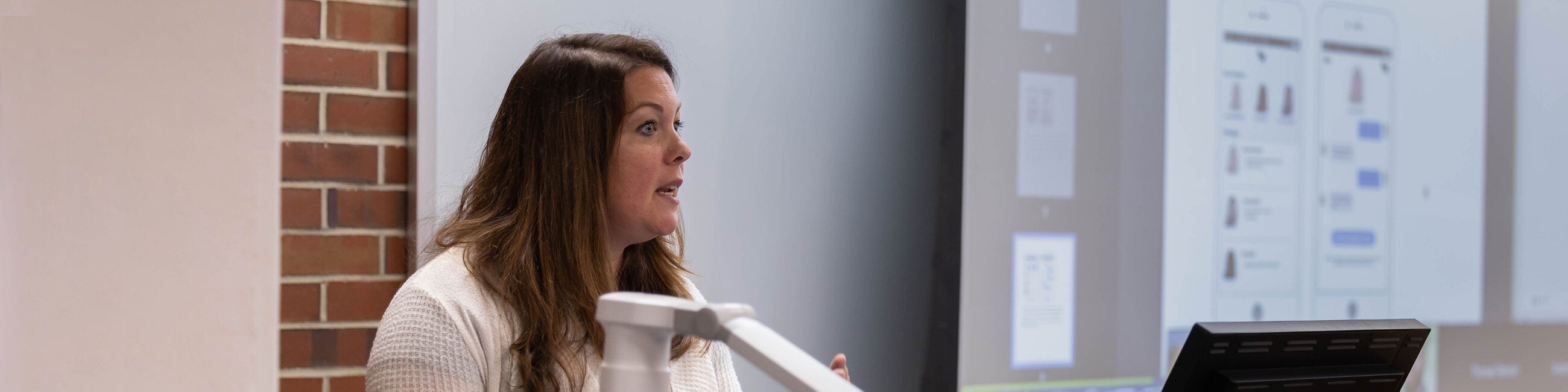 Female professor lecturing at the front of class.  