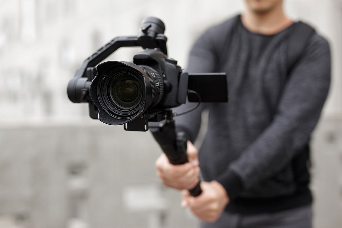 A close up shot of someone holding a DSLR camera.