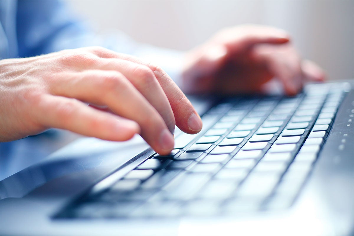 Close up shot of a man typing on a keyboard.