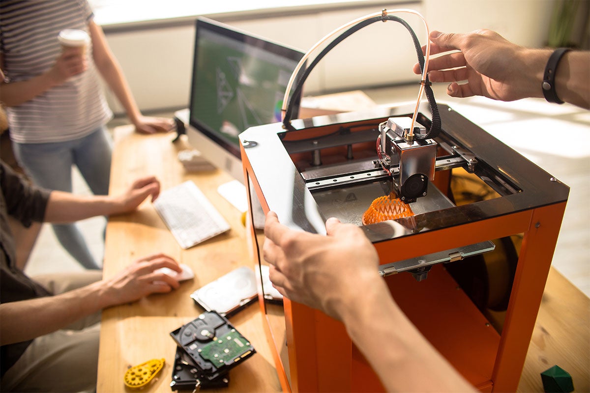 Close up of people using a 3D printer.